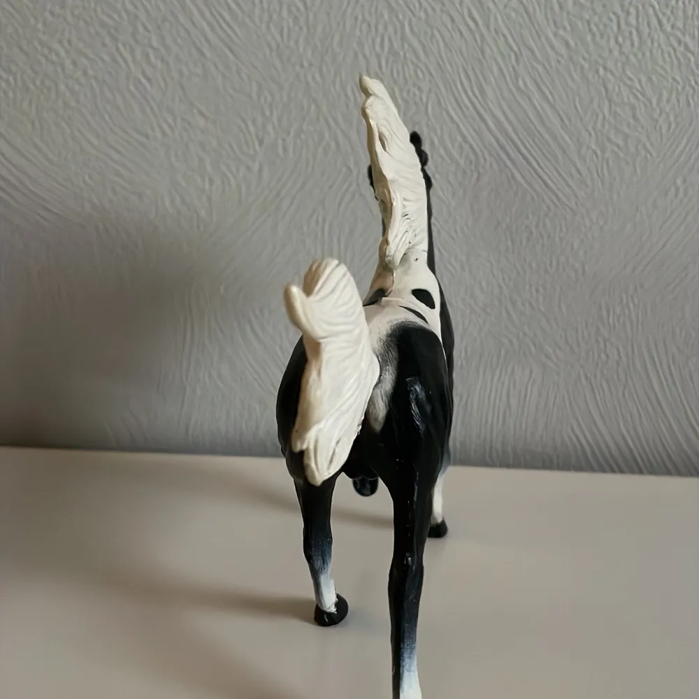 Säljer en detaljerad hästfigur i svart och vitt. Hästen har en elegant pose med fladdrande man och svans. Perfekt för samlare eller som dekoration.. Muu.