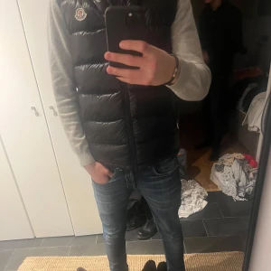 Svart dunväst Moncler - Snygg svart dunväst från Moncler med dragkedja och hög krage. Skick 10/10. Storlek s.