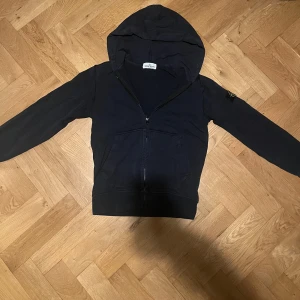 Mörkblå huvtröja från Stone Island Junior - Säljer en snygg mörkblå stone island zip up. Skick ungefär 8/10 och har storleken ungefär 152. Skriv till mig om ni har några funderingar! Pris kan diskuteras!