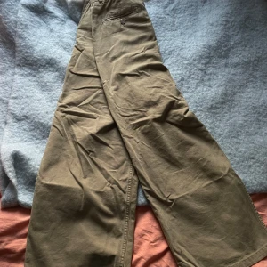 Beige byxor från Weekday - Säljer ett par snygga beige byxor från Weekday i storlek 48. De har en loose passform och är perfekta för både vardag och avslappnade tillfällen. Byxorna är i bra skick och har en klassisk design med knappar och dragkedja. Perfekta för höst och vår!