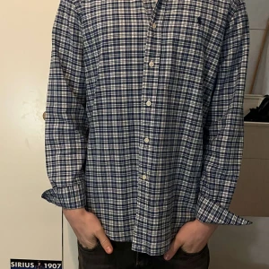Rutig skjorta från Ralph Lauren - Tja, Säljer en snygg rutig skjorta från Ralph Lauren i blått och vitt. Modellen är 180cm och väger 65Kg. Inga defekter. Fraktar samma dag som köp görs. Hör av er i Pm vid frågor. Mvh 