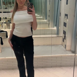 Vit offshoulder topp - Säljer en stilren vit offshoulder topp som är perfekt för både fest och sommar. Toppen har en tight passform och ärmlös design som ger en elegant look. Passar utmärkt till både jeans och kjol för en chic outfit.