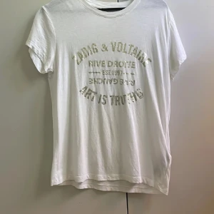 Vit t-shirt från Zadig & Voltaire - Vit Zadig Voltaire T-shirt som använts ca 2-3 gånger men har defekter som syns på bilderna. Inget som syns när man har tröjan på, därför så billigt pris 