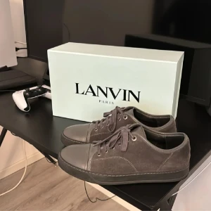 Lanvins - Säljer ett par stilrena grå sneakers från Lanvin i mycket bra skick. Skorna är gjorda av skinn och mocka med snygg snörning framtill. Perfekta för både vardag och fest! Kommer med originalkartong. Storlek 41 passar upp till 43 för mig