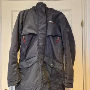Mörkblå parkas  från Didriksons strl 38 - Säljer en mörkblå parkasjacka från Didriksons i bra skick. Jackan har praktiska fickor med knappar och dragkedja, samt en huva för regniga dagar. Innerficka med dragkedja och en med öppen ficka. Relativt rymlig modell. Perfekt för höst och vinter!