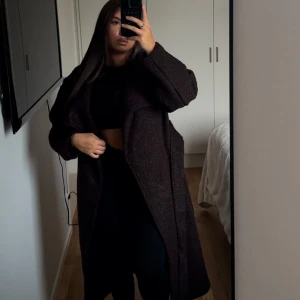 Mörkbrun kappa - Säljer en snygg mörkbrun kappa i mycket bra skick. Den är lång och har en loose passform, perfekt för höst och vinter. Kappan har långa ärmar och en stilren design utan knappar eller dragkedja. Supermysig och stilren för kalla dagar! Helt ny med prislapp kvar från Gina Tricot i storlek XS men skulle säga att denne passar S också💕slutsålt på hemsidan