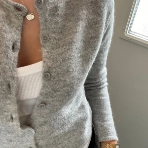 Grå kofta från KappAhl - Säljer en supermjuk och stilren grå kofta från KappAhl i storlek XS. Perfekt för både vardag och kontor. Den har långa ärmar och knappar framtill. Passar perfekt över en topp eller klänning för en lager-på-lager-look.🩶Lite nopprig                ❗️Den första bilden är inte min❗️