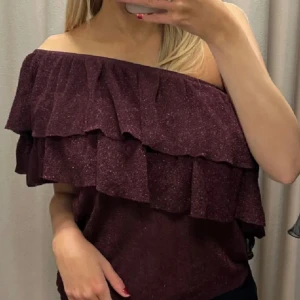 Vinröd offshoulder topp med volanger - Säljer en superfin vinröd offshoulder topp från mango. Den har flera lager av volanger och glittrig som gör den perfekt för fest eller jul. Den är i storlek L, men passar mig som har storlek S☺️ skriv gärna om ni har frågor eller vill ha fler bilder!!