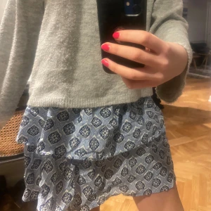 Blå mönstrad kjol från Gina Young - Säljer en superfin blå kjol med ett unikt mönster. Kjolen har volanger som ger en extra touch av stil. Perfekt för sommarens alla tillfällen! 💙
