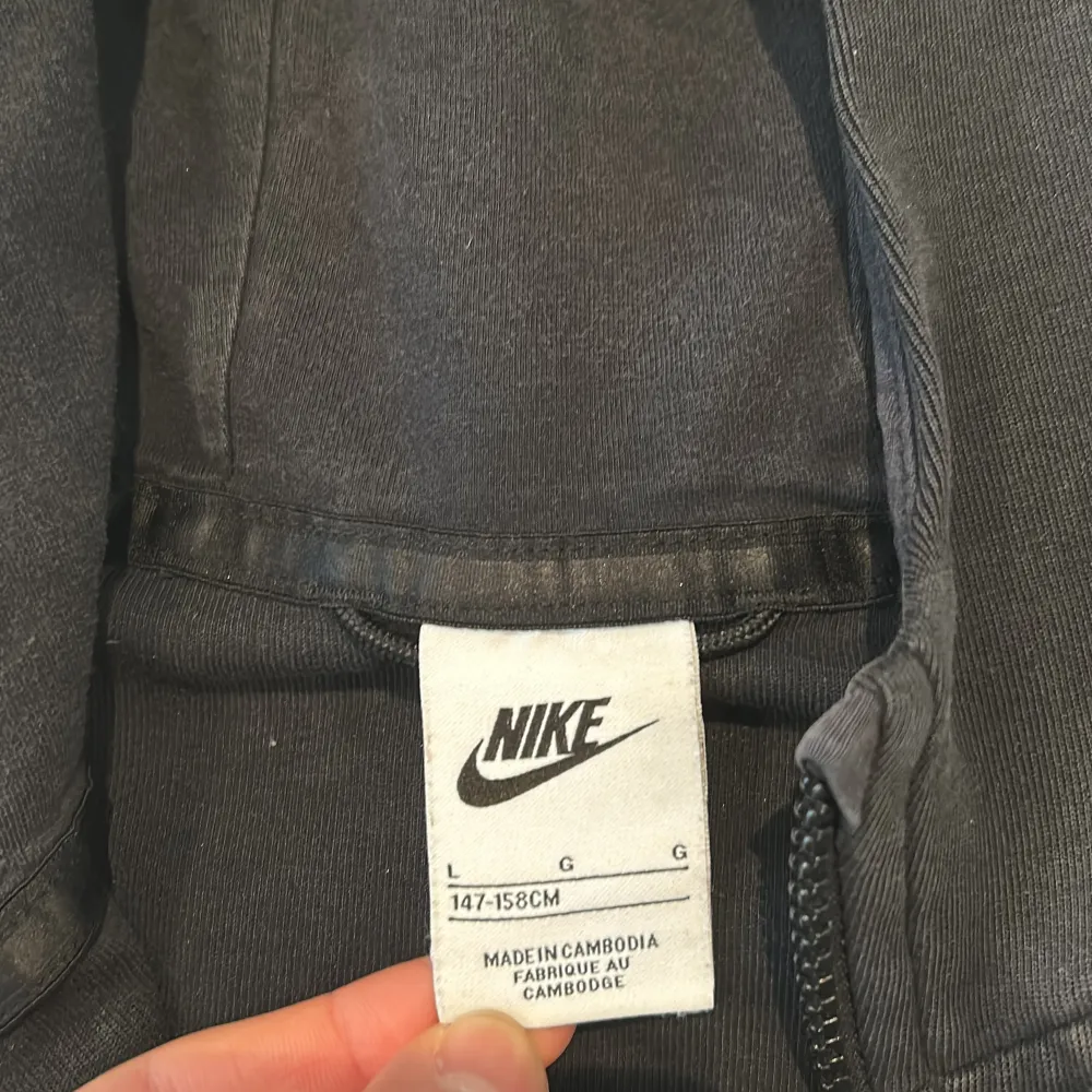 Säljer en grå svart Nike tech flece. Den är väldigt sunki så det blir väldigt lågt pris. Det är storlek 147-158cm. Hoodies.