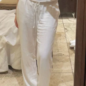 Vita linnebyxor med snörning - Säljer ett par vita linnebyxor i mycket bra skick. De har en avslappnad passform med snörning i midjan för en bekväm känsla. Perfekta för sommardagar eller en avslappnad stil. Passar till både vardag och semester!
