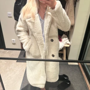 Vit teddyjacka - Mysig vit teddyjacka i mycket bra skick. Perfekt för höst och vinter med sin långa ärm och knappar framtill. Jackan har en loose passform och är superbekväm att ha på sig. Den är både stilren och varm, vilket gör den idealisk för kyligare dagar.