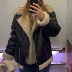 Svart skinnjacka med foder - Säljer en snygg svart skinnjacka med mysigt vitt foder. Jackan har en cool dragkedja och långa ärmar med fodrade muddar. Perfekt för höst och vinter när du vill hålla dig varm och stilren. Passar till både vardag och fest! Köpt från mango för 1200kr 