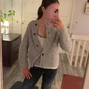 Grå stickad kofta - Mysig grå stickad kofta med knappar framtill. Perfekt för kyliga dagar och passar bra över en t-shirt eller linne. Koftan har en avslappnad passform och långa ärmar, vilket gör den idealisk för både höst och vinter. Ett måste i garderoben för en stilren och bekväm look! ❤️nästan aldrig använd❤️