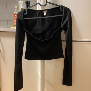 Svart långärmad topp - Snygg svart långärmad topp i ett stretchigt material. Perfekt för både vardag och fest. Den har en enkel och stilren design som gör den lätt att matcha med olika outfits. Toppen är i bra skick och redo för en ny ägare!
