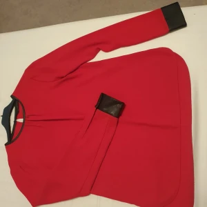 Röd tröja från Zara - Snygg röd tröja från Thomas Rath med svarta detaljer vid hals och ärmslut. Perfekt för både vardag och fest. Den har en stilren design och är i mycket bra skick. Passar perfekt till höst- och vintergarderoben.