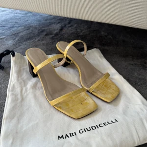 2 st färgglada klackskor från Mari Giudicelli  - Säljer två par klackskor från Mari Giudicelli i storlek 38. Ett par i ljusgul och ett i korallröd, båda med fyrkantig tå och klack. ( säljs tillsammans ) 