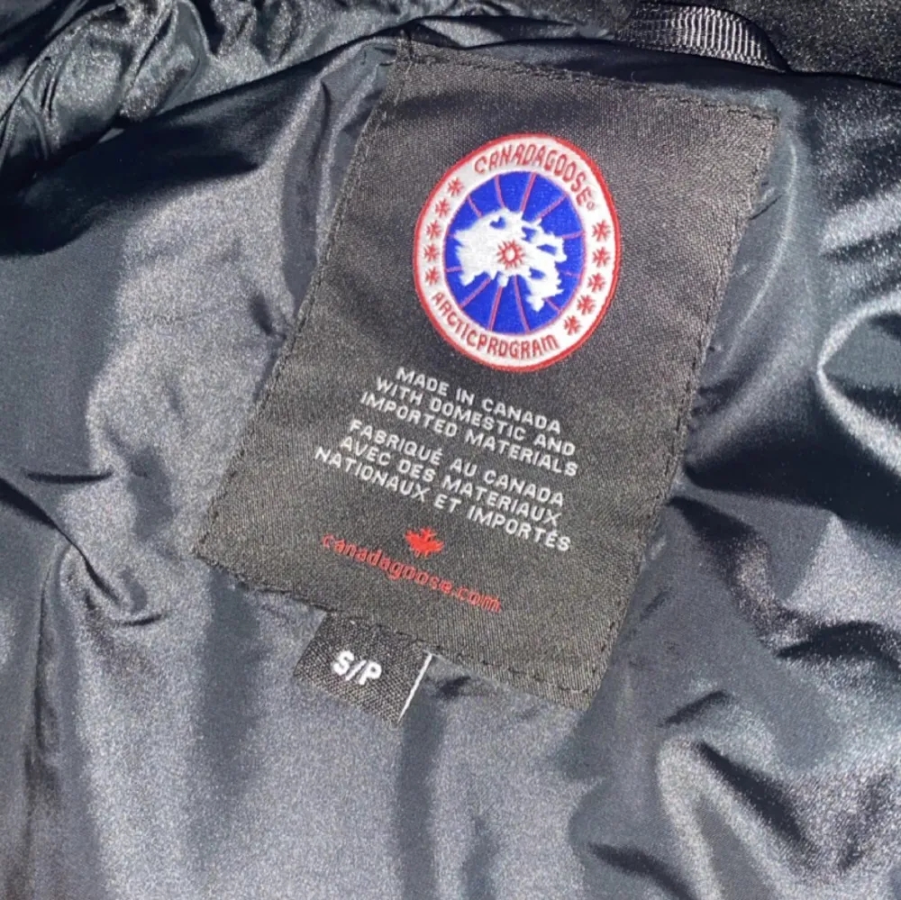 Säljer en svart dunväst från Canada Goose i mycket bra skick. Västen har en broderad logga på bröstet och stängs med dragkedja och knappar. Perfekt för kyliga höst- och vinterdagar. Storleken är S, pris kan diskuteras . Jackor.