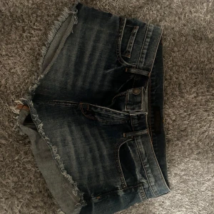 Mörkblå jeansshorts med fransar - Säljer ett par snygga mörkblå jeansshorts från Brittany Blue. De har en fransig kant och klassisk femficksdesign. Perfekta för sommardagar och är använda 2-3 ggr så har inga tecken på användning 💕