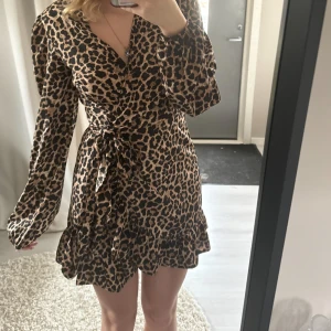 Leopardmönstrad omlottklänning - Jätte fin leopardmönstrad omlottklänning med volangdetaljer och knyt i midjan. Klänningen har långa ärmar.Materialet känns lätt och bekvämt.