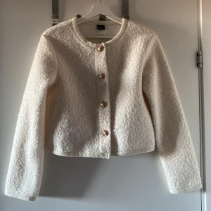 Vit croppad jacka med knappar🤍 - Säljer en superfin vit croppad jacka med snygga knappar framtill. Den är perfekt för både höst och vår och har en mysig, lite fluffig textur. Jackan är långärmad och passar perfekt till både jeans och kjol. Ett måste i garderoben för en stilren look!🤍