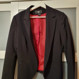 Kavaj - Svart figursydd kavaj med rött foder, kort modell.