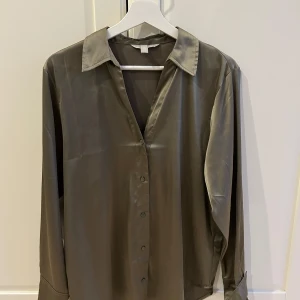 Grön sidenblus - Elegant grön blus i siden-look med klassisk krage och knappar framtill. Perfekt för en stilren look.