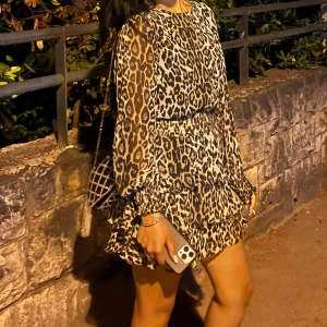 Leopardmönstrad klänning - Trendig leopardmönstrad klänning med volanger och långa ärmar. Perfekt för en kväll ute med vänner. Klänningen har en lös passform och är tillverkad i ett lätt material som ger en bekväm känsla.