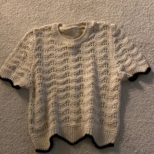 Stickad tröja  - Säljer en beaige stickad tröja med ett vågmönster och svarta kanter. Den är från Zara och är en kortare modell i perfekt skick