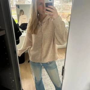 Beige hoodie - Mysig beige hoodie med luva och dragsko. Perfekt för en avslappnad stil. Tröjan har långa ärmar och en lös passform. Från Lindex 