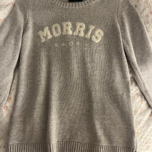 Grå tröja från Morris Lady - Säljer en stilren grå tröja från Morris Lady i 100% bomull. Tröjan har långa ärmar och ett ribbstickat mönster vid hals, ärmslut och nederkant. Perfekt för en avslappnad och bekväm stil men även för en middag som du kan piffa upp med smycken. använd fåtal gånger💗