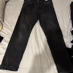 Svarta jeansbyxor - Snygga svarta jeansbyxor med en klassisk straight passform. De har en midwaist design och är perfekta för en avslappnad stil. Byxorna har traditionella fem fickor och en knappgylf. Storlek 33/32