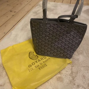 Grå/mörkgrå tote väska  - Storlek small ( s ) grå färgad Tote bag! Dustbag medföljs. Aldrig använd. Man får plats med mycket dock. En riktig look-alike Kan gå ner i pris vid snabb affär💞