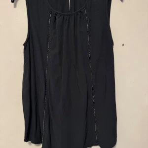 Svart ärmlös topp från Street One - Snygg svart ärmlös topp från Street One med diskreta sömmar framtill. Perfekt för en stilren look. Toppen har en rund halsringning och ett lätt fall.