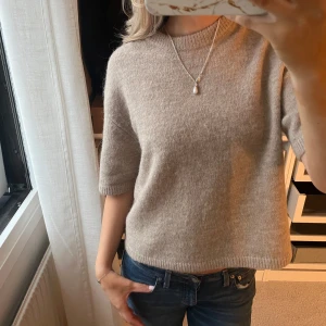Beige stickad tröja från Gina Tricot - Säljer en stilren beige trekvartsärmad stickad tröja från Gina Tricot, deras premium Quality i alpacka ull blandning. Tröjan har korta ärmar och en rund halsringning.💕