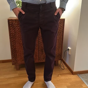 Vinröda/mörlila chinos - Snygga vinröda/mörklila chinos med normal passform. Byxorna har en klassisk design med knappar och dragkedja framtill. Perfekta för en stilren look. tiger of Sweden, str 48
