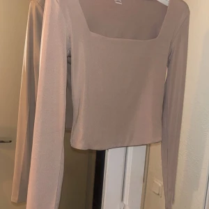 Beige långärmad topp från New yorker - Snygg beige långärmad topp från Amisu med en fyrkantig. Tillverkad i ett mjukt och bekvämt material och helt oanvänd.