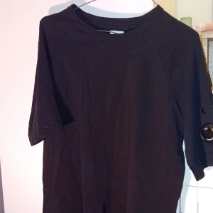 Svart tröja från C.P. Company - Snygg svart tröja från C.P. Company med en unik detalj på ärmen. Tröjan har en stilren design och är perfekt för dig som gillar mode med funktion. Den är tillverkad i ett slitstarkt material och har en knappdetalj vid ärmen.