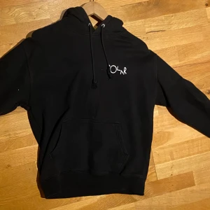 Svart hoodie från Polar storlek S - Säljer en svart hoodie från Polar med en stor vit logga på ryggen och en mindre logga på bröstet. Tröjan har en klassisk känguruficka och justerbar huva med snören. Perfekt för en avslappnad stil. Storlek S