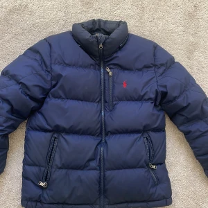 Blå dunjacka från Polo Ralph Lauren - Säljer en snygg blå dunjacka från Polo Ralph Lauren. Finns luva till om man vill ha! Den har inga hål och nästan oanvänd, säljer för jag har två styckna! Hör av dig för att snacka priser💕