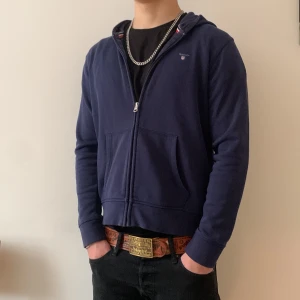 Mörkblå huvtröja från GANT - Säljer en stilren mörkblå Gant hoodie med dragkedja. Tröjan är  storlek Xs och är för liten för mig som är 168 cm lång. Inga tecken på användning och varken defekter heller. Mitt pris 250kr hör gärna av dig om du har frågor eller är intresserad hälsningar Alex 