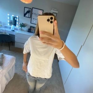 Vit t-shirt från Zara - Säljer en enkel och stilren vit t-shirt från Zara. Den har en normal passform och korta ärmar, perfekt för en avslappnad look. Tillverkad i mjukt bomullsmaterial för extra komfort.