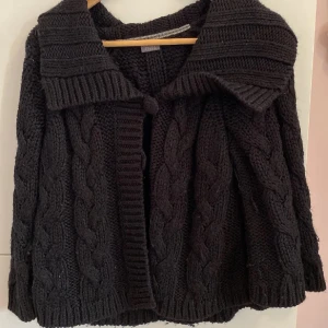 Svart stickad kofta med flätmönster - Mysig svart stickad kofta med ett snyggt flätmönster. Koftan har en stor krage och knäppning framtill💖💖💖storlek L men sitter fint på mig som har S! 