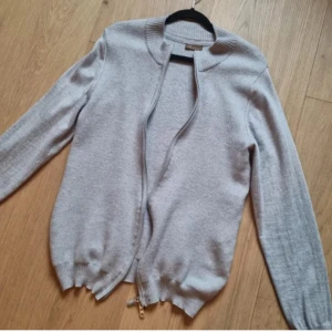 Zip tröja Stenströms - Snygg och stilren grå/beige kofta från Stenströms med dragkedja framtill. Den har en ribbad krage och långa ärmar, perfekt för kyligare dagar. Passar bra till både vardag och mer uppklädda tillfällen. Ny skick. pris kan diskuteras vid snabb affär