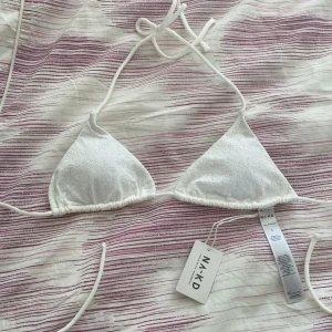 Vit bikiniöverdel från NA-KD - Snygg vit bikiniöverdel från NA-KD med triangelformade kupor och knytband i nacken och ryggen. Perfekt för sommarens stranddagar. Enkel och stilren design som passar till det mesta. Helt ny, men för liten på mig