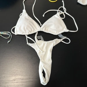 Bikini - Snygg vit ribbad bikini med knytband. Toppen har justerbara axelband och byxan har en enkel design. Perfekt för soliga dagar på stranden eller vid poolen.