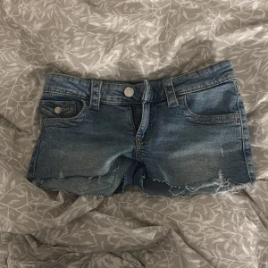 Blå jeansshorts med fransar - Snygga blå jeansshorts med fransiga kanter och klassisk femficksdesign. Perfekta för en avslappnad sommarlook. De har en knapp och dragkedja framtill för enkel stängning. Xs/152