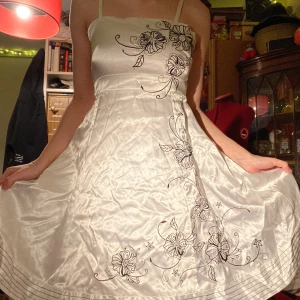 Vit klänning med blommigt mönster från Kappahl - vit klänning från Kappahl med svart blommigt mönster och lite paljetter. har smala axelband och dragkedja baktill. ganska liten i bysten. 