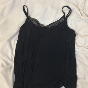Svart linne med spetsdetaljer - Snyggt svart linne med smala axelband och spetsdetaljer vid halsringningen, från Esprit