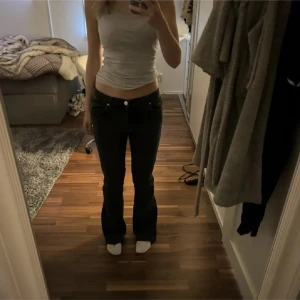 Svarta jeansbyxor - Snygga svarta jeansbyxor med låg midja och bootcut-stil. Perfekta för en avslappnad look. Längd 31. Lite slitningar längst ner men inget som märks av.